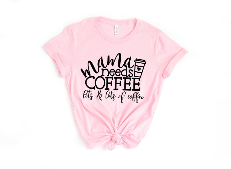 Puede incluir: Camiseta rosa con texto negro que dice "mama needs coffee lots & lots of coffee" y una ilustraci&oacute;n en blanco y negro de una taza de caf&eacute;.