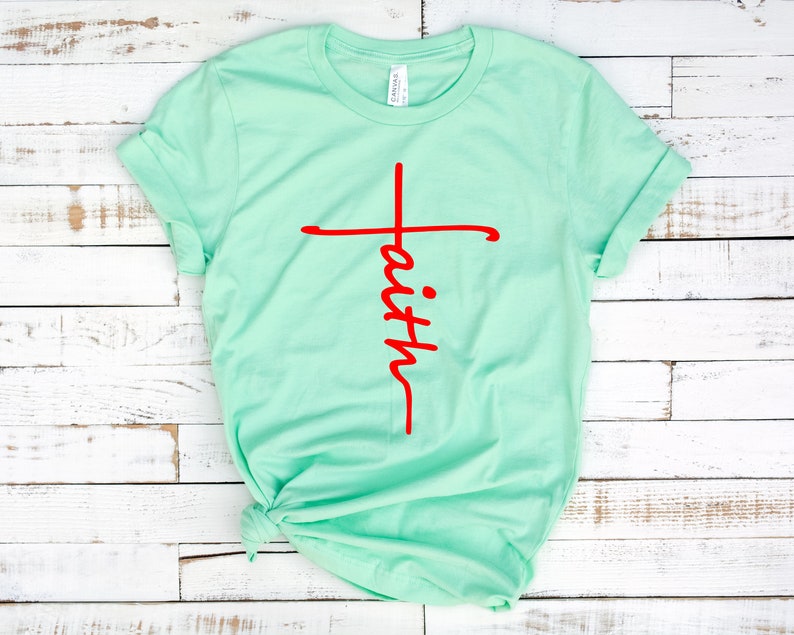 May include: A light green t-shirt with a red cross and the word "faith" written vertically down the cross.