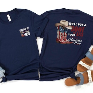 May include: Two navy blue t-shirts. One shirt has a small graphic with text that reads "BROUGHT TO YOU COURTESY OF WHITE & BLUE". The other shirt has a graphic of cowboy boots and a hat with the text "WE'LL PUT A BOOT IN YOUR ASS American Way".