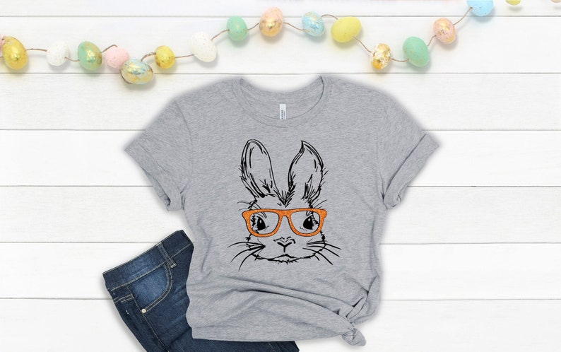 May include: A gray t-shirt with a black and white illustration of a bunny wearing orange glasses.