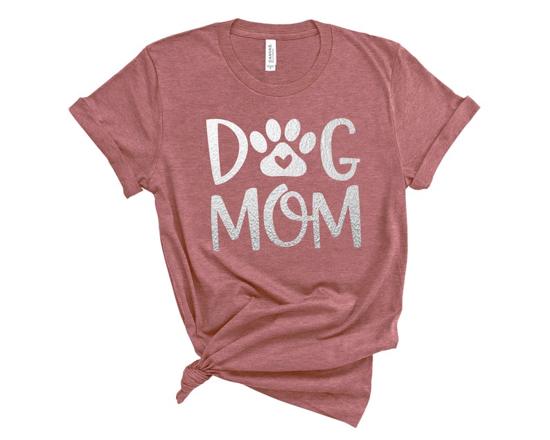 Pode incluir: Uma camiseta marrom com o texto "Dog Mom" em branco com uma pegada de pata e um design de cora&ccedil;&atilde;o.