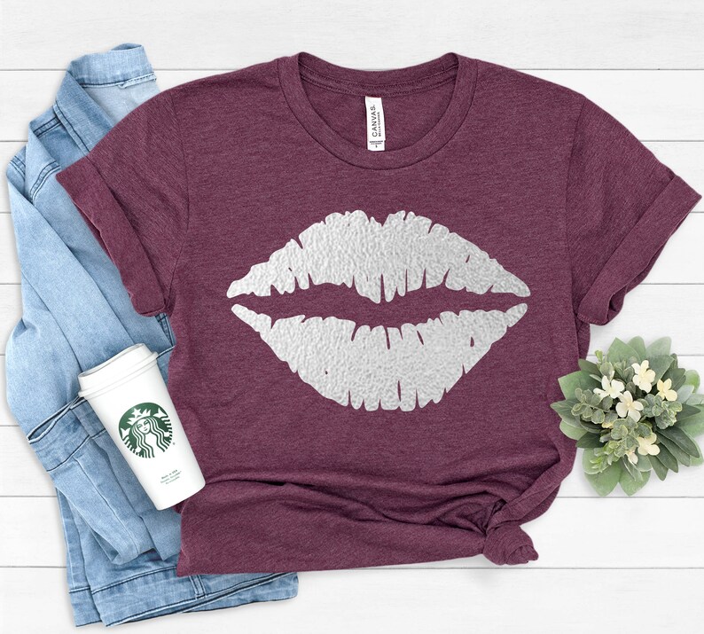 May include: A maroon t-shirt with a white glitter-like lip print design.