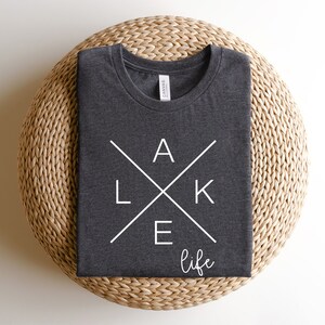 May include: A dark gray t-shirt with a white graphic design that says "LAKE life" with the letters "LAKE" forming a cross.