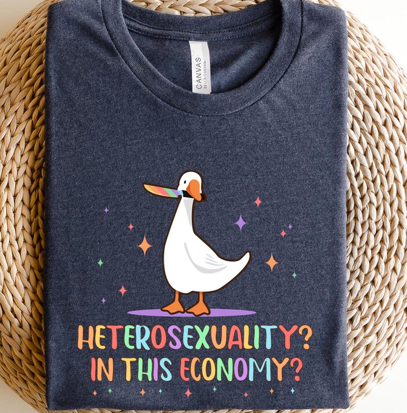 K&ouml;nnte beinhalten: Ein dunkelblaues T-Shirt mit einer wei&szlig;en Gans, die einen Regenbogen-Lolli im Schnabel h&auml;lt. Der Text "Heterosexuality? In this economy?" ist unter der Gans aufgedruckt.