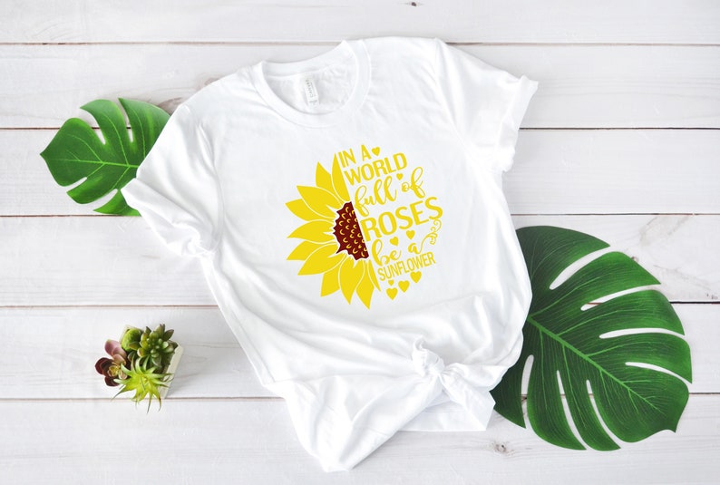 May include: White t-shirt with a yellow sunflower graphic and the text "In a world full of roses be a sunflower".