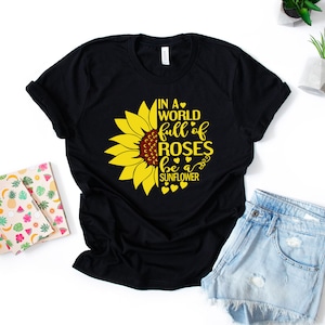 May include: Black t-shirt with a yellow sunflower graphic and the text "In a world full of roses be a sunflower".