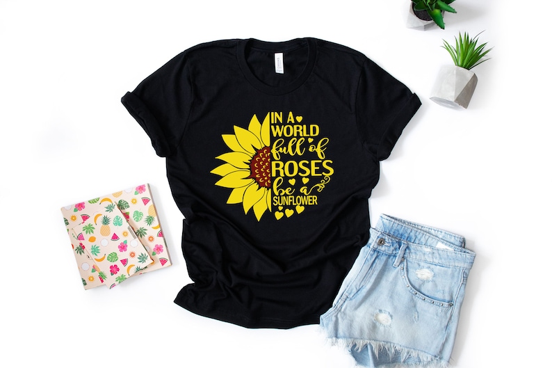 May include: Black t-shirt with a yellow sunflower graphic and the text "In a world full of roses be a sunflower".