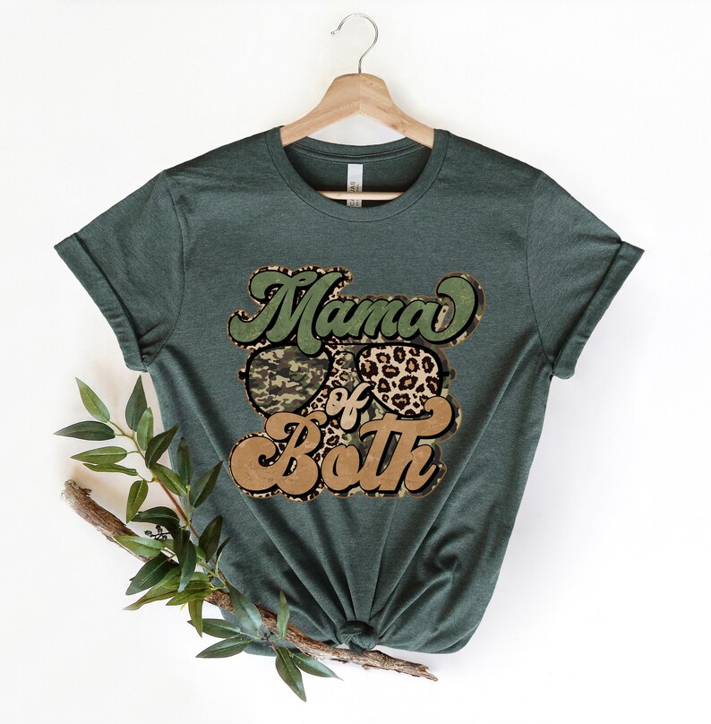 May include: A green t-shirt with the text "Mama of Both" in a retro font. The text is surrounded by a camouflage pattern and a leopard print.