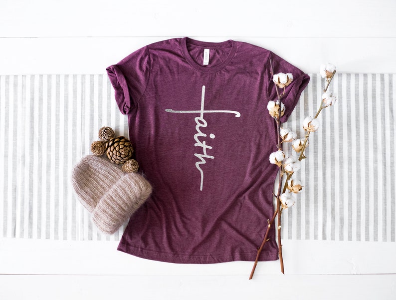 May include: A maroon t-shirt with a white cross and the word "faith" written vertically on the front.