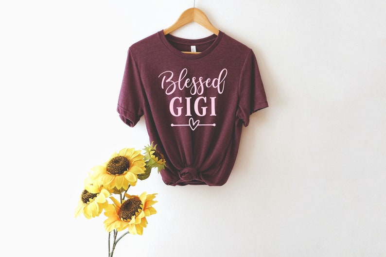 May include: Burgundy t-shirt with the text "Blessed Gigi" in pink lettering and a small pink heart.