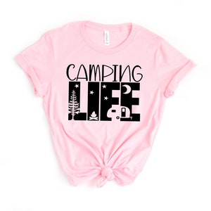 May include: Pink t-shirt with black text that reads "Camping Life" with a graphic of a camper, a campfire, a tree, and stars.