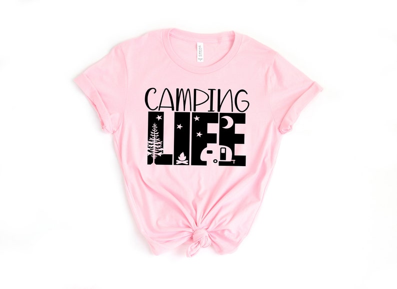 May include: Pink t-shirt with black text that reads "Camping Life" with a graphic of a camper, a campfire, a tree, and stars.