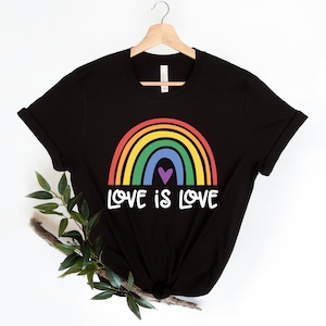 Puede incluir: Camiseta negra con un gr&aacute;fico de arco&iacute;ris y el texto "LOVE IS LOVE".