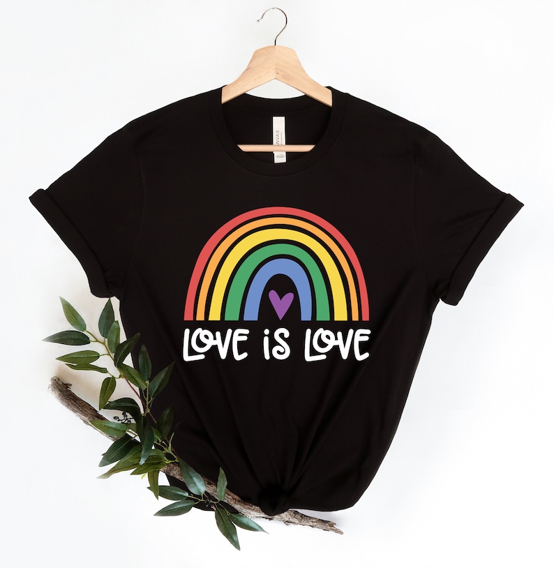 Puede incluir: Camiseta negra con un gr&aacute;fico de arco&iacute;ris y el texto "LOVE IS LOVE".