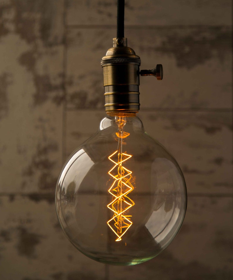 May include: A vintage-style light bulb with a clear glass globe and a coiled filament. The bulb is hanging from a cord and has a brass socket.
