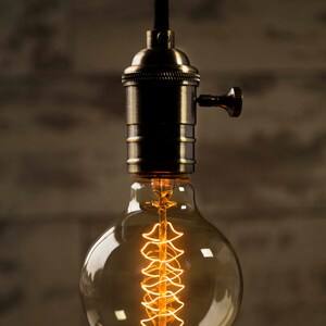 May include: A vintage-style light bulb with a coiled filament, hanging from a black cord and a brass socket.
