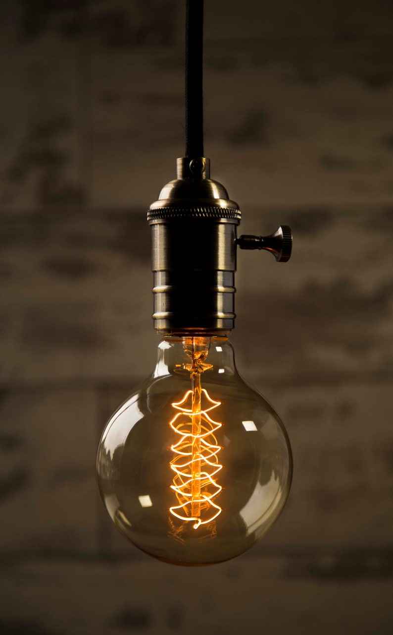 May include: A vintage-style light bulb with a coiled filament, hanging from a black cord and a brass socket.