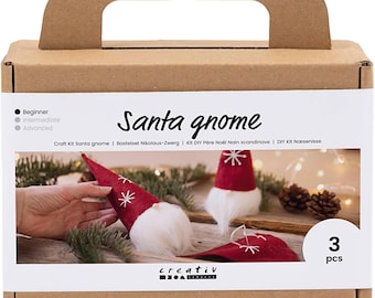 Puede incluir: Un kit de manualidades para hacer tres gnomos de Santa Claus. La caja muestra una foto de los gnomos terminados y el texto "Santa gnome".