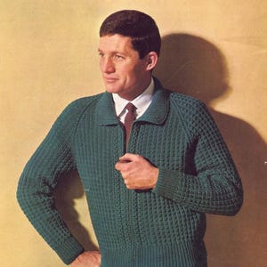 May include: A green knitted cardigan with a zipper closure. The cardigan has a waffle stitch pattern and a collar. The text "Double Knittings by Patons" and "Three sizes to fit 38-42 inch chest" is printed on the top of the image.
