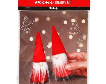 Puede incluir: Un kit creativo con dos gnomos de fieltro rojo con ribete de piel blanca y narices de madera. El kit incluye todo lo necesario para crear estos adorables gnomos, perfectos para añadir un toque festivo a la decoración de tu hogar.