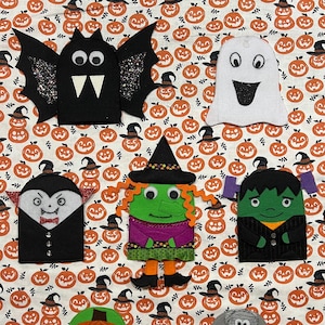 May include: Set of six felt Halloween finger puppets. The puppets include a bat, ghost, vampire, witch, Frankenstein, and mummy. The puppets are all black, white, green, and orange.