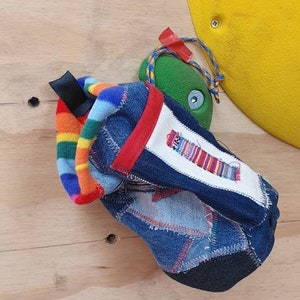 May include: A blue denim drawstring bag with a rainbow fleece lining and a red trim. The bag is made from recycled denim and has a patchwork design.