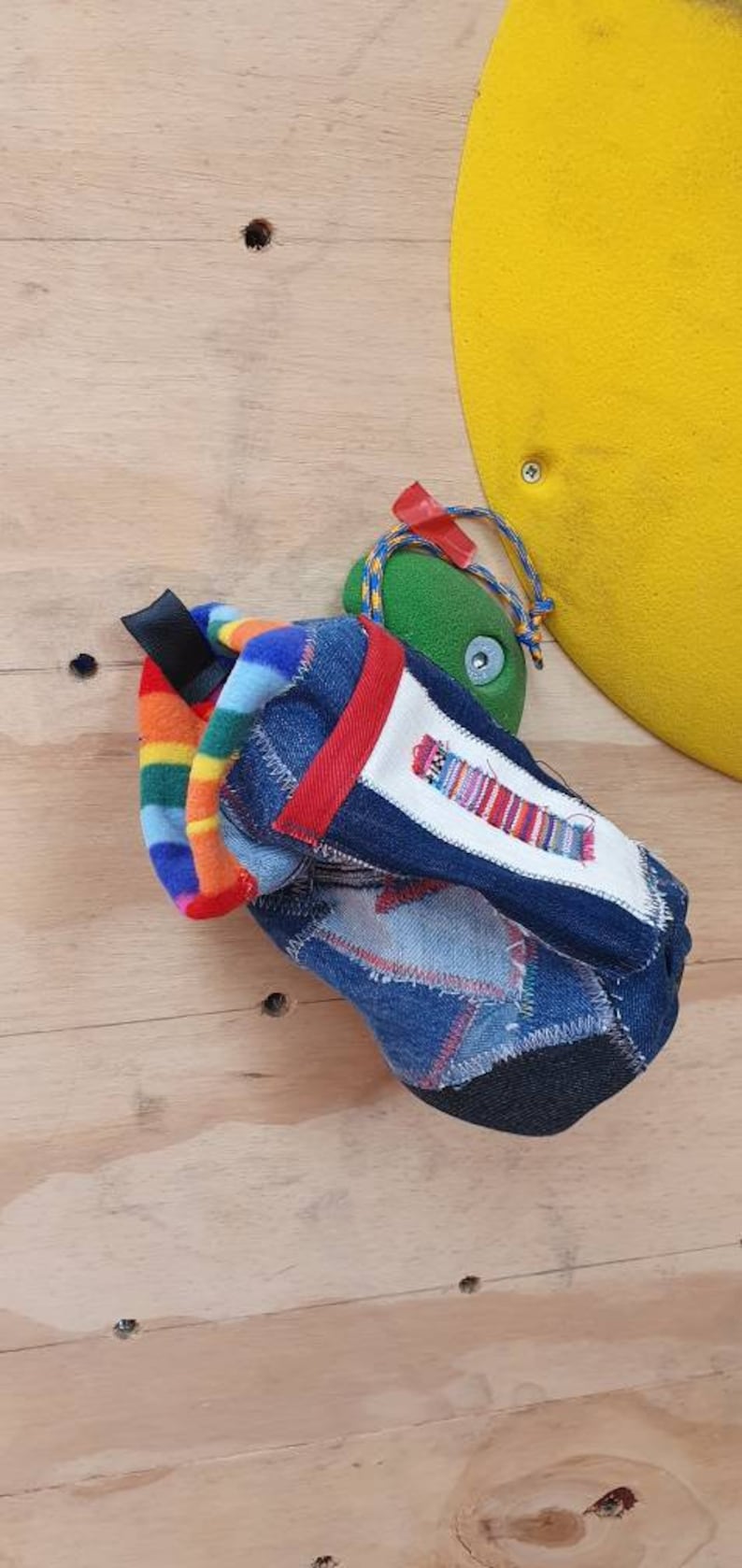 May include: A blue denim drawstring bag with a rainbow fleece lining and a red trim. The bag is made from recycled denim and has a patchwork design.