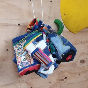 May include: A collection of colorful fabric scraps sewn together to create a unique and decorative hanging. The fabric scraps include paisley patterns, stripes, and denim.