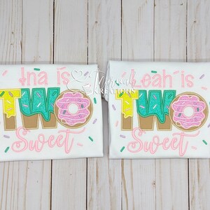 Może przedstawiać: Dwie białe koszulki z napisem "Ina is Two Sweet" i "Leah is Two Sweet" w kolorze r&oacute;żowym, zielonym, ż&oacute;łtym i brązowym. Cyfra dwa jest ozdobiona grafiką pączka.