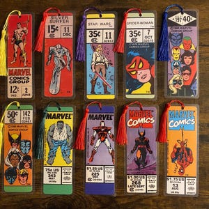 May include: A collection of Marvel Comics bookmarks featuring various characters like Silver Surfer, Spider-Woman, and Hulk. Each bookmark has a tassel and comic book art, with prices and dates visible.