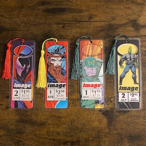 May include: Four rectangular bookmarks featuring comic book character illustrations and the Image logo. Each bookmark includes a colored tassel, issue numbers, month, and price text. The designs display various figures in vibrant colors with printed text including image, issue numbers, months, and prices in dollars.