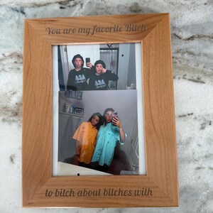Puede incluir: Un marco de fotos de madera clara con dos fotos. La foto superior muestra a dos personas haciéndose un selfie. La foto inferior muestra a dos personas haciéndose un selfie. El marco tiene el texto "You are my favorite Bitch" y "to bitch about bitches with".