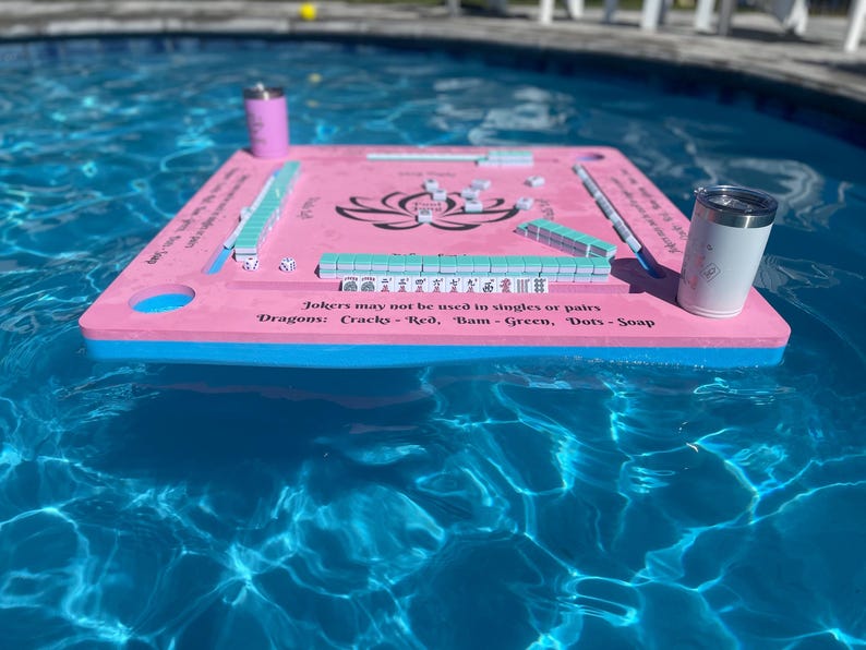 Puede incluir: Un tablero de juego flotante rosa y azul con fichas blancas y el texto "Jokers may not be used in singles or pairs Dragons: Cracks-Red, Bam-Green, Dots-Soap".