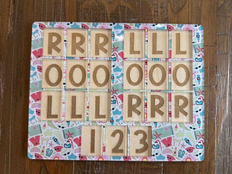 May include: A rectangular wooden puzzle board featuring a colorful summer-themed pattern of flip-flops, sunglasses, and watermelons. The board contains cutouts holding wooden tiles engraved with the letters R, L, O, and the numbers 1, 2, and 3.