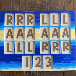 May include: A rectangular wooden puzzle board featuring a blue and yellow painted gradient background. The board contains multiple square cutouts, each holding a wooden tile engraved with the letters R, L, A, or the numbers 1, 2, and 3.