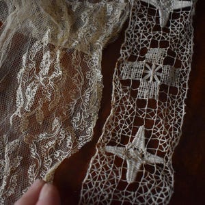 May include: Close-up of antique lace textiles in cream and off-white. One piece features floral patterns, while another showcases a geometric design with star and cross motifs. A ruler shows measurements in inches.