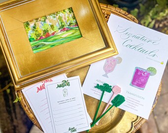May include: A set of Masters-themed party supplies, including a framed painting of a golf course, a cocktail menu with two signature drinks, "Azalea" and "Transfusion", and a scorecard with the text "The Masters" and "Saturday, April 8, 2023".