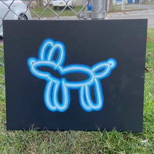 May include: A blue and white balloon animal shaped like a dog painted on a black canvas.