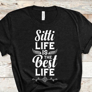 May include: Black t-shirt with white text that reads "Sitti Life is the Best Life" with wings and a floral design.