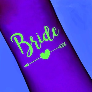 May include: A purple surface with the word "Bride" in bright green script. A green heart and arrow design is below the word, pointing to the right. The background is a gradient of purple and blue.