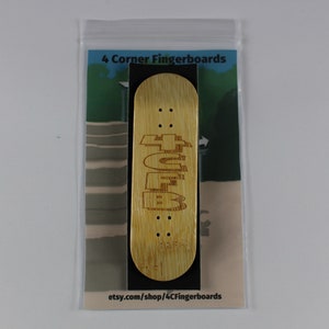 May include: A wooden fingerboard with the text "4CF" engraved on it. The fingerboard is in a clear plastic bag with a white background and the text "4 Corner Fingerboards" and "etsy.com/shop/4CFingerboards".