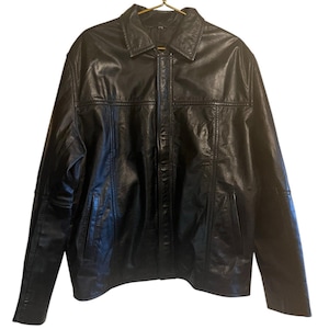 May include: A black leather jacket with a collared neckline and a front zipper closure. The jacket has two front pockets and is hanging on a gold hanger. The leather appears to be slightly textured.