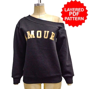 May include: Black off-the-shoulder sweatshirt with gold lettering that says "AMOUR".