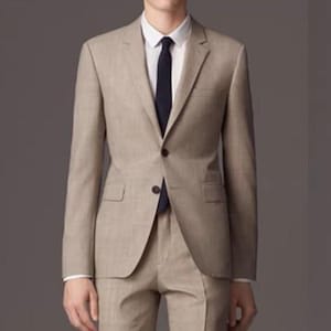 May include: A beige suit with a single-breasted jacket and a dark blue tie.
