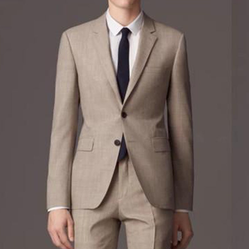 May include: A beige suit with a single-breasted jacket and a dark blue tie.