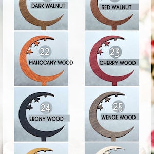May include: A set of eight crescent moon cake toppers in different wood colors. The colors include dark walnut, red walnut, mahogany wood, cherry wood, ebony wood, wenge wood, oak wood, and natural wood. Each topper has a number and the name of the wood color printed on it.
