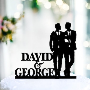 May include: Black silhouette cake topper of two grooms in suits with the text "DAVID & GEORGE" below.