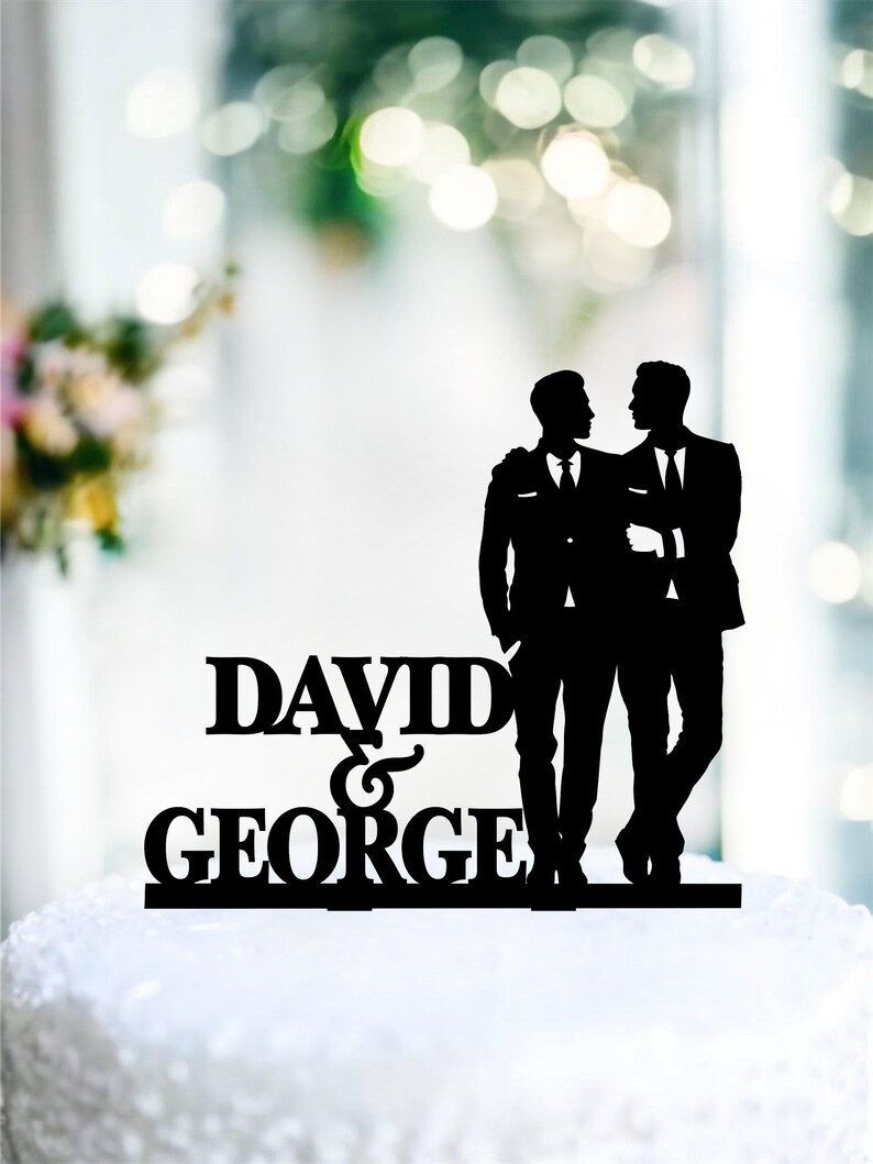 May include: Black silhouette cake topper of two grooms in suits with the text "DAVID & GEORGE" below.