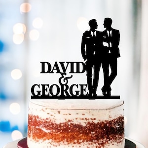 May include: Black silhouette cake topper of two grooms in suits with the text "DAVID & GEORGE" underneath.
