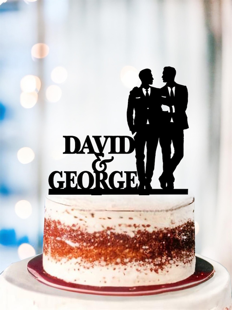 May include: Black silhouette cake topper of two grooms in suits with the text "DAVID & GEORGE" underneath.